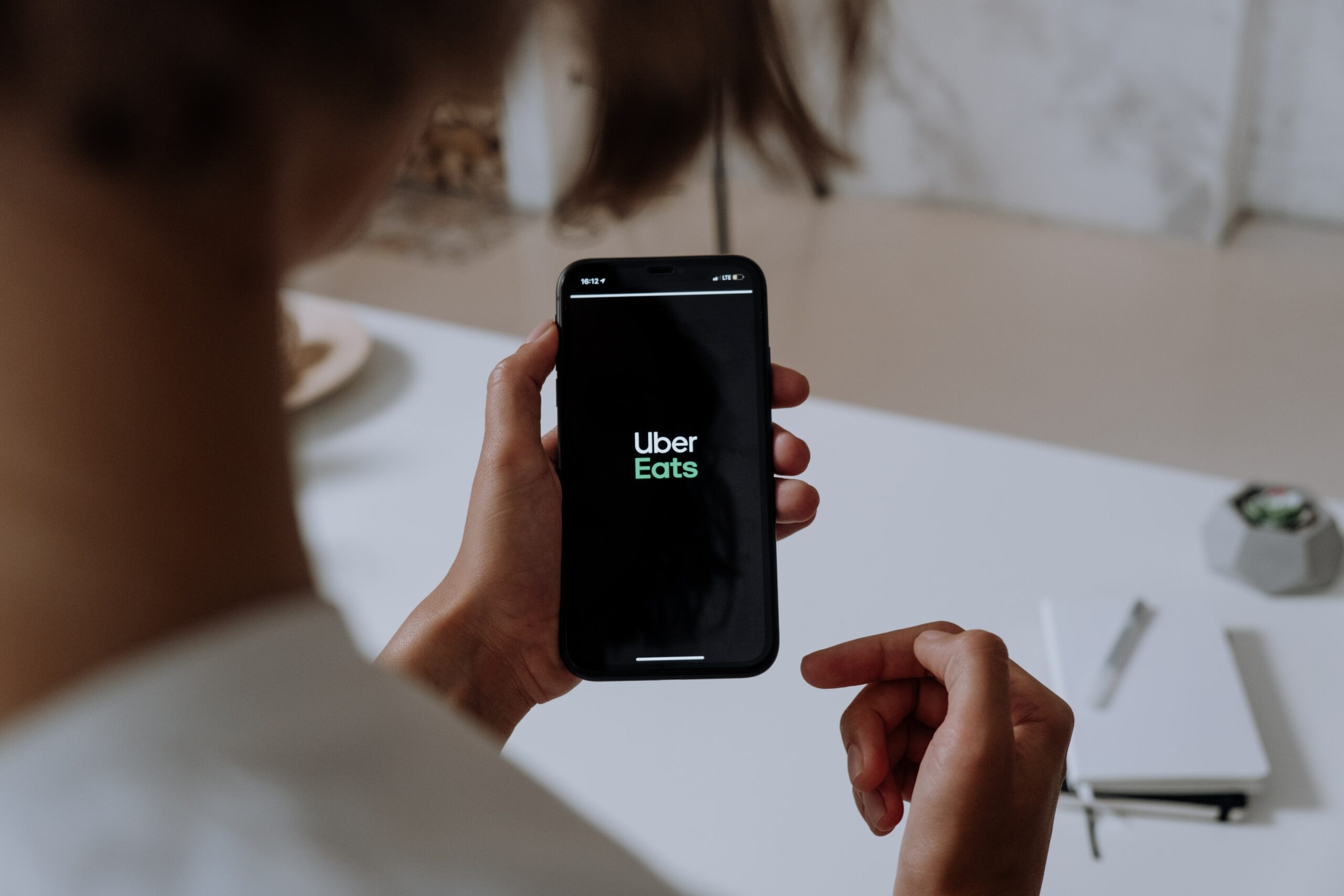 A girl holds a smartphone with Uber Eats logo on the screen.