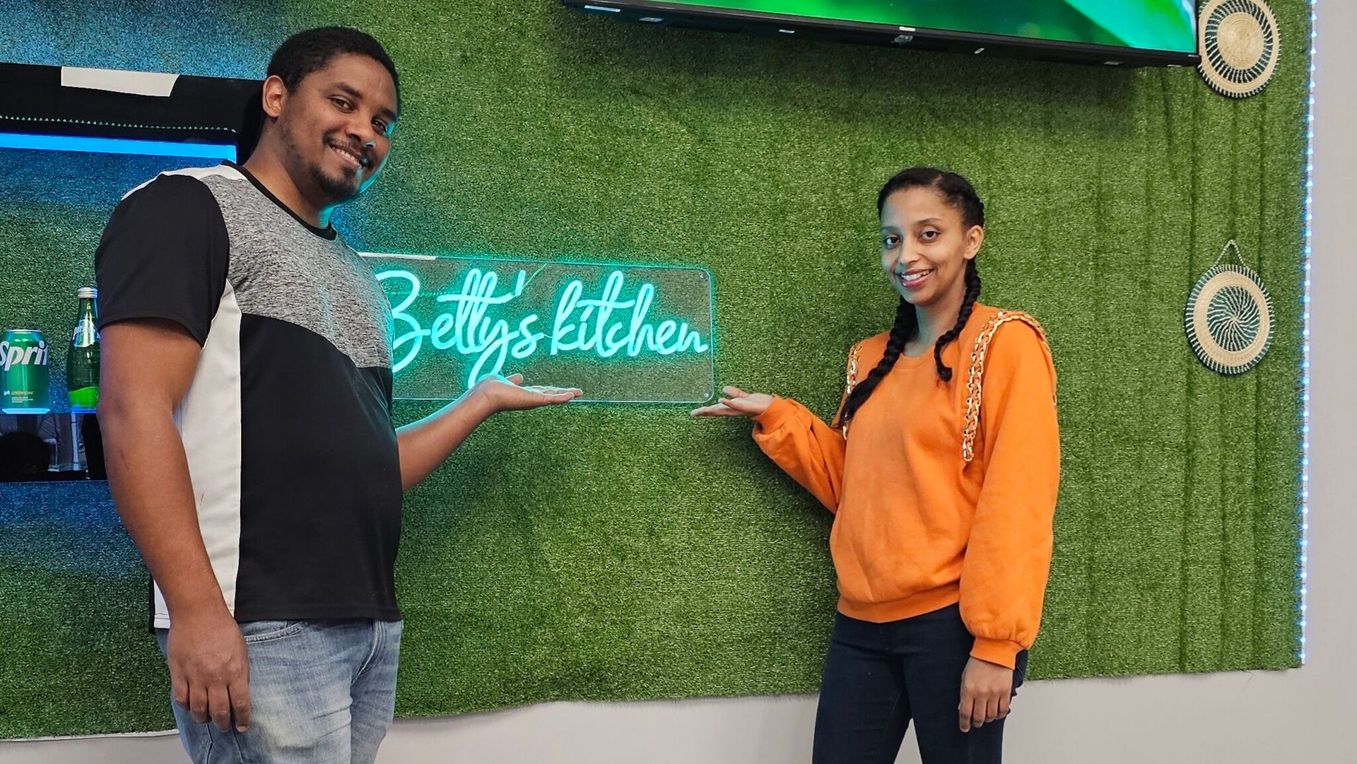 Two young people point the Betty's kitchen logo and pose for the picture.