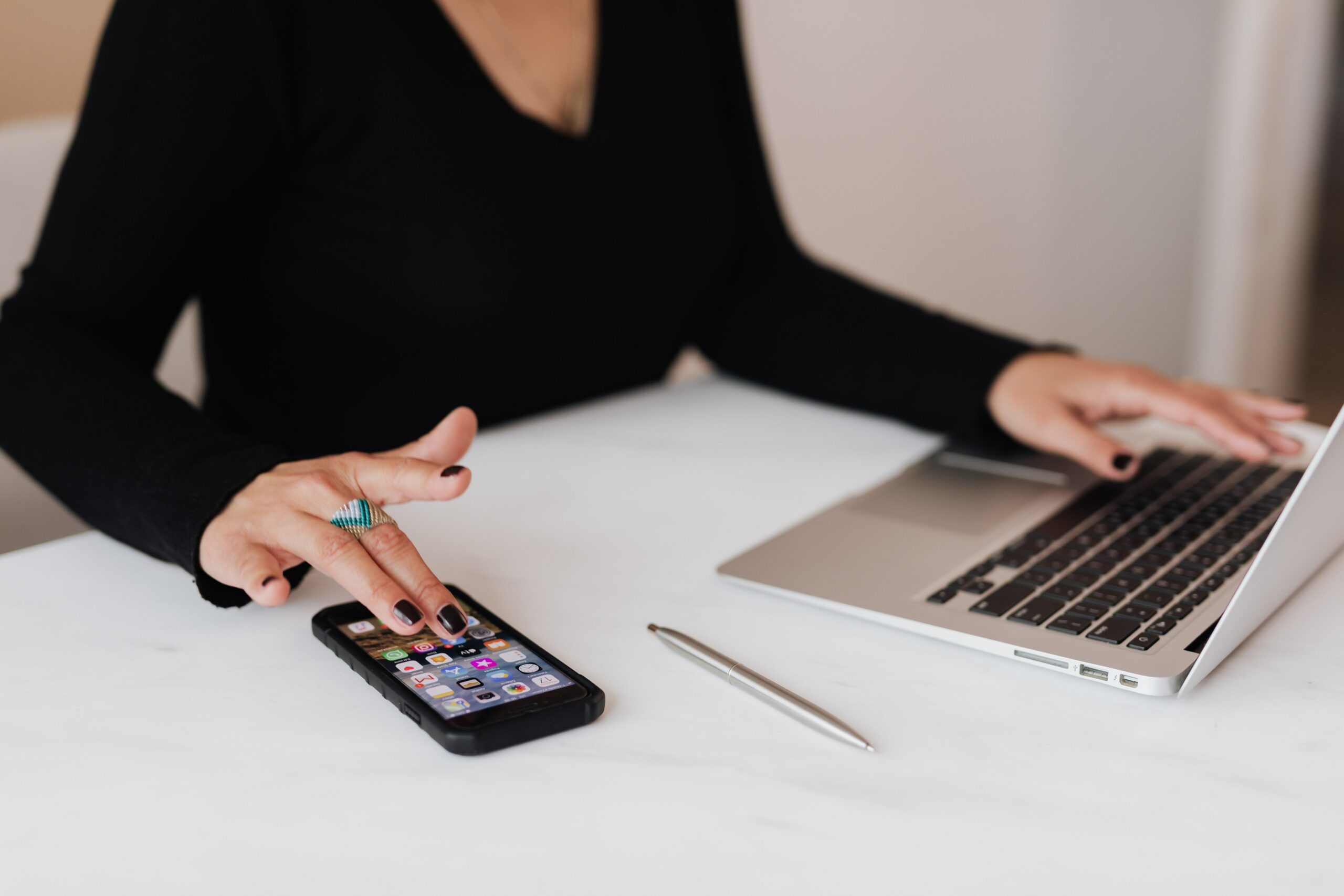 A woman is working with her laptop and smartphone.