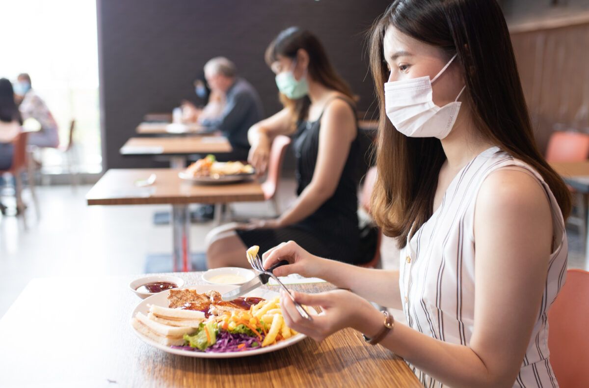 People are having lunch in the restaurant wearing masks.