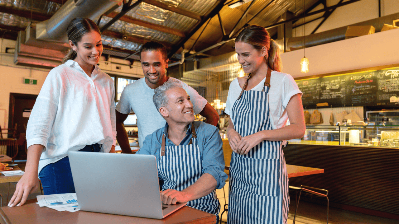 Waiters look at the laptop and have a discussion with happy faces.