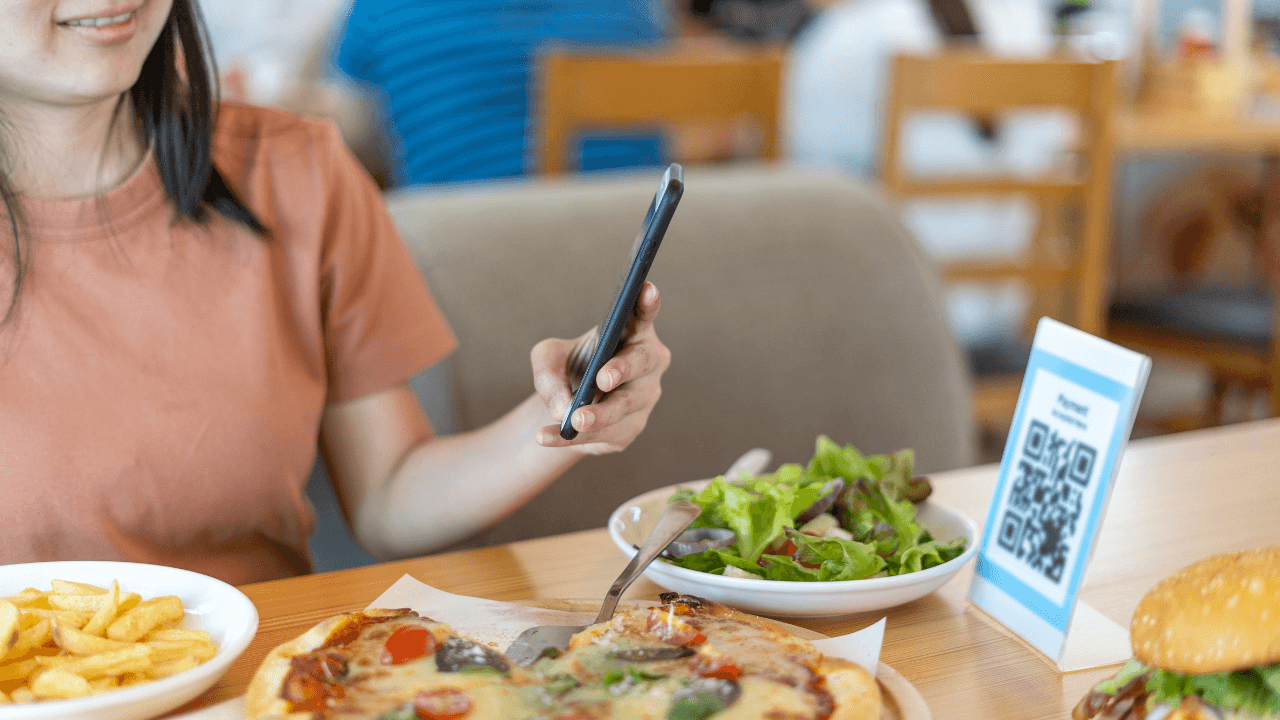 A customer takes a QR code with her smartphone while having a lunch in the restaurant.