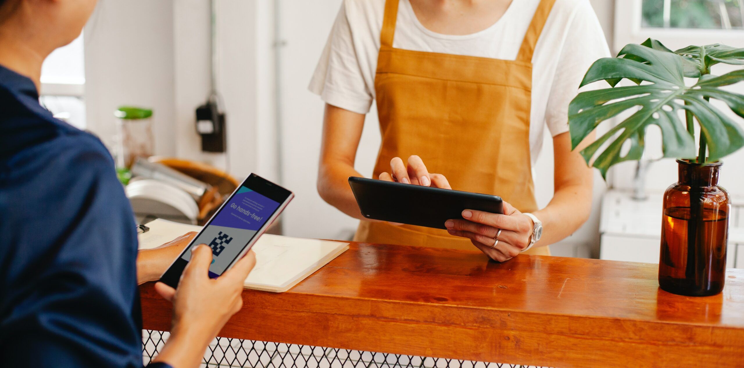 A casher is taking an order in his tablet from the customer.