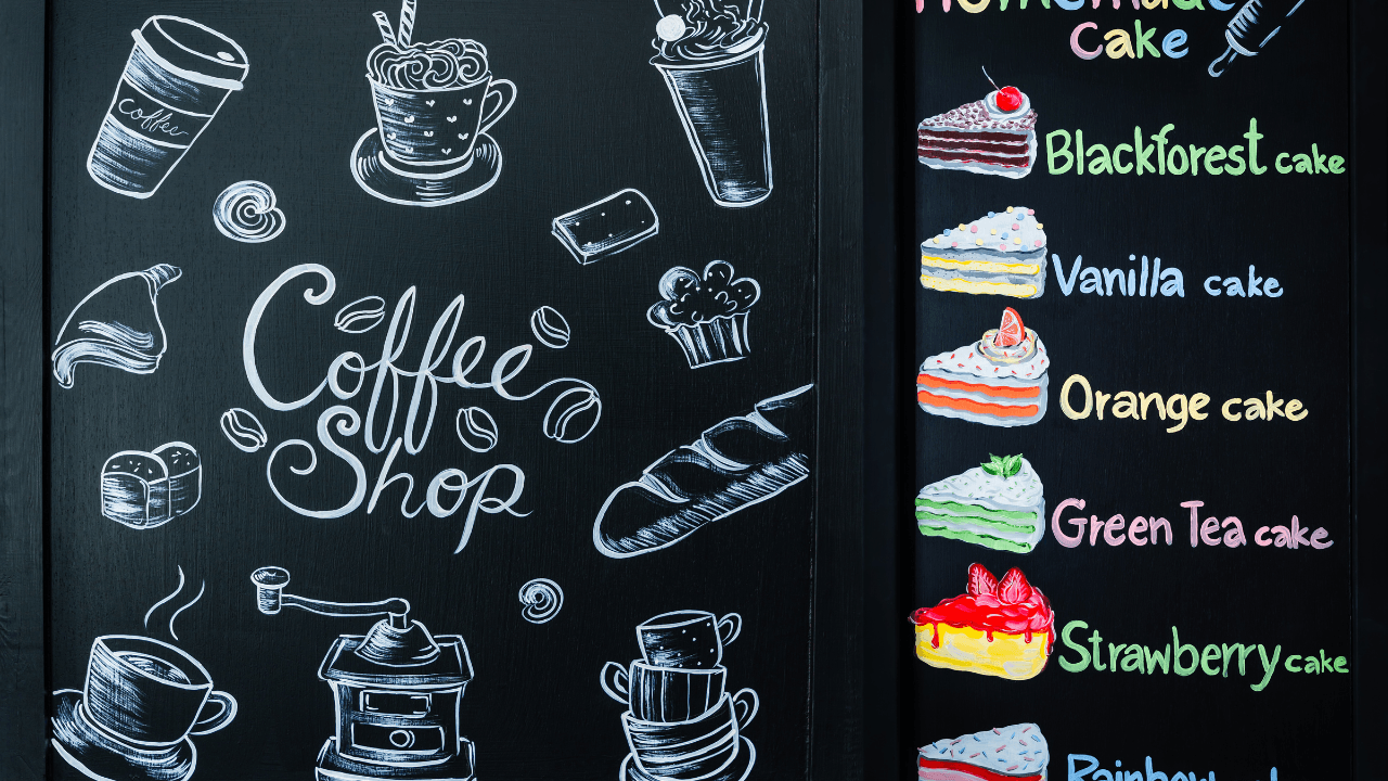 A coffee-shop blackboard with drawings of different cakes.