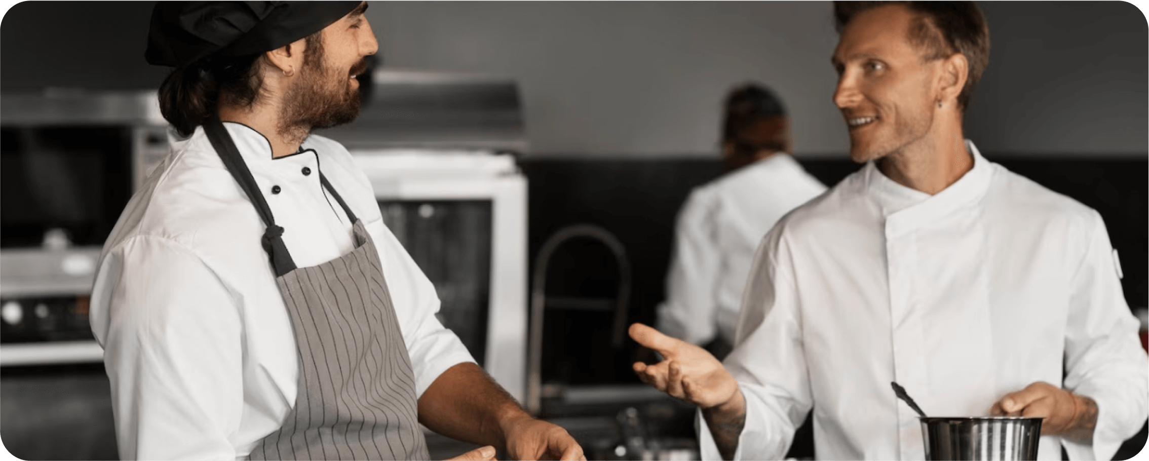 Two cooks are talking to each other in the kitchen.