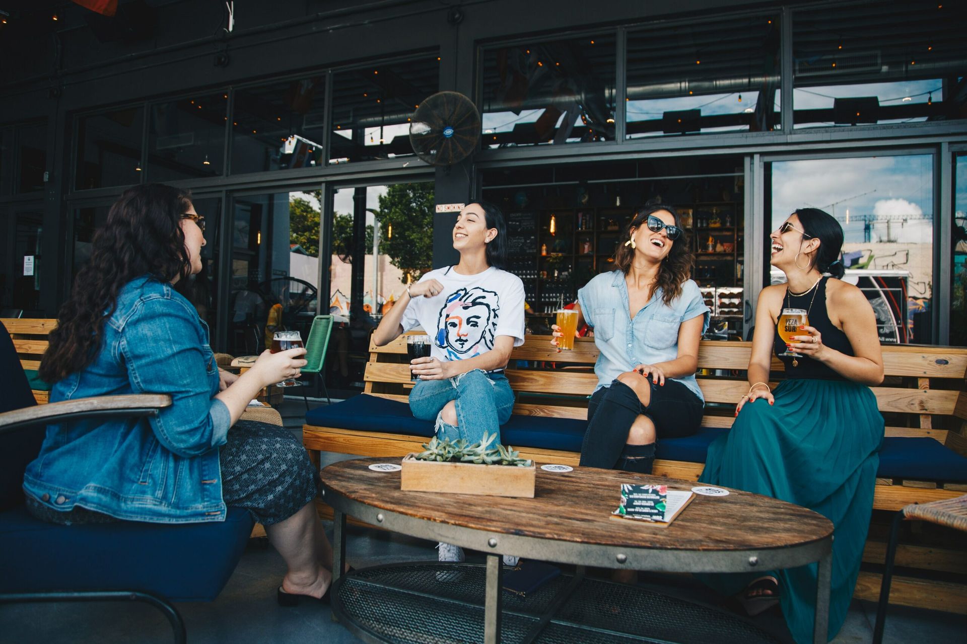 Four young ladies drink beer and laugh.