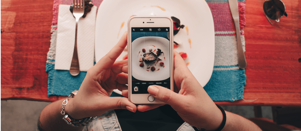 A girl takes a picture of her dinner with her smartphone.