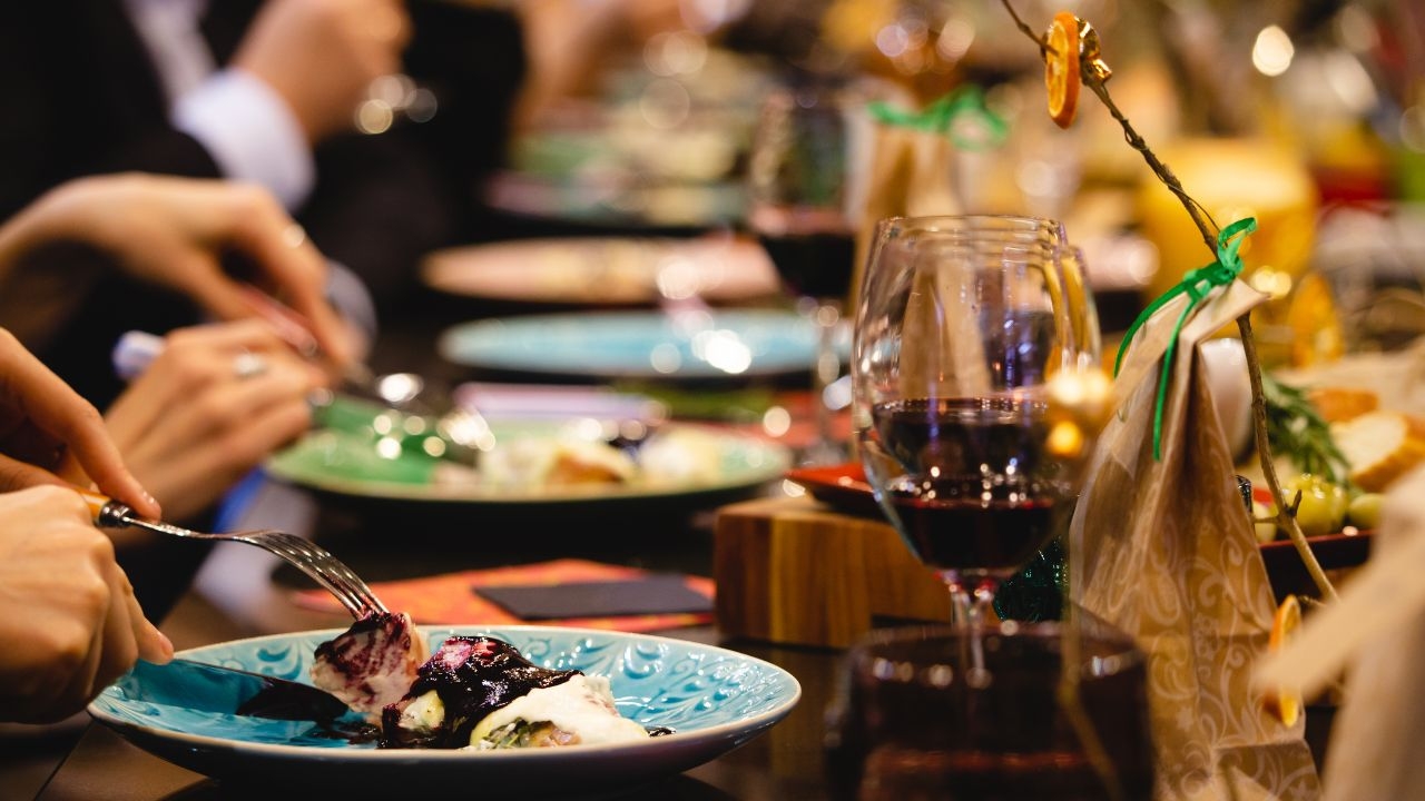 A restaurant table with a glasses of wine and different plates with dishes.